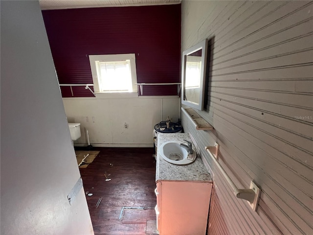 bathroom featuring hardwood / wood-style flooring, sink, toilet, and wood walls