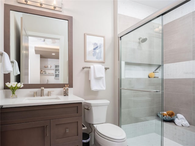 bathroom featuring vanity, a shower with shower door, and toilet