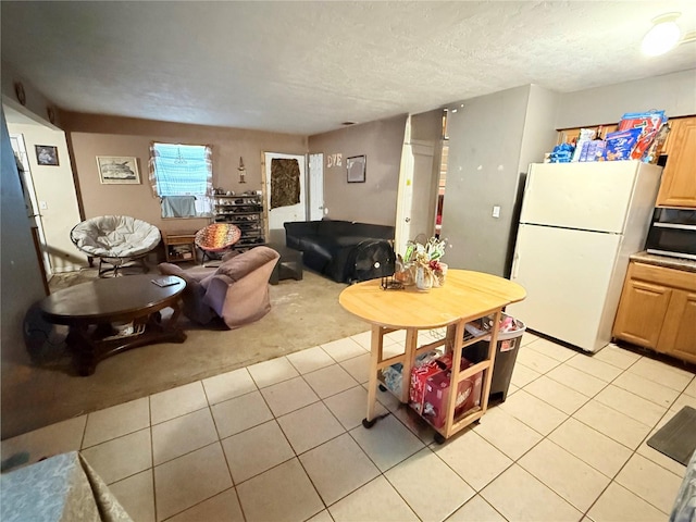 kitchen with light brown cabinets, a textured ceiling, white fridge, and light tile patterned floors