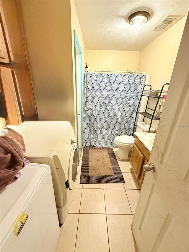 bathroom featuring tile patterned flooring, a textured ceiling, toilet, vanity, and washer and dryer