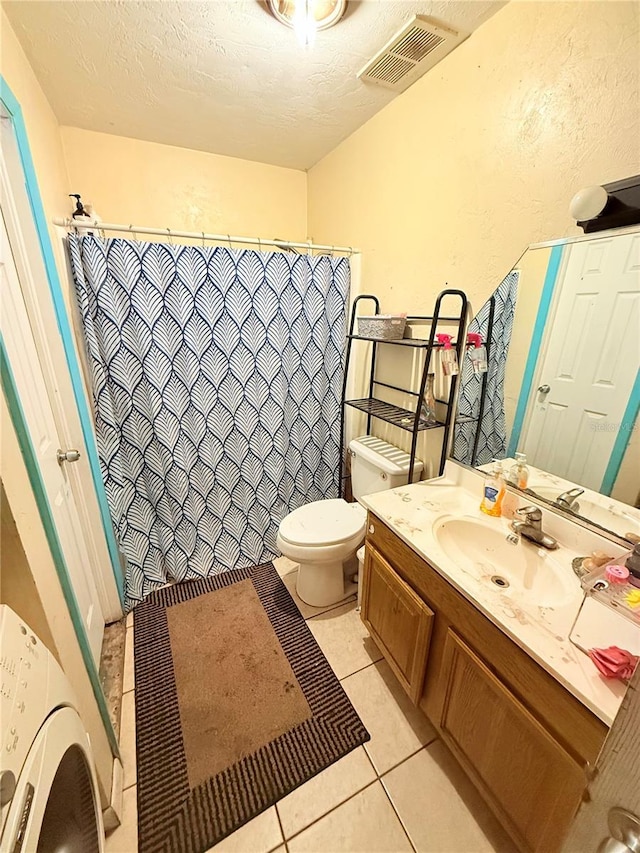 bathroom with tile patterned floors, washer / clothes dryer, a textured ceiling, toilet, and vanity