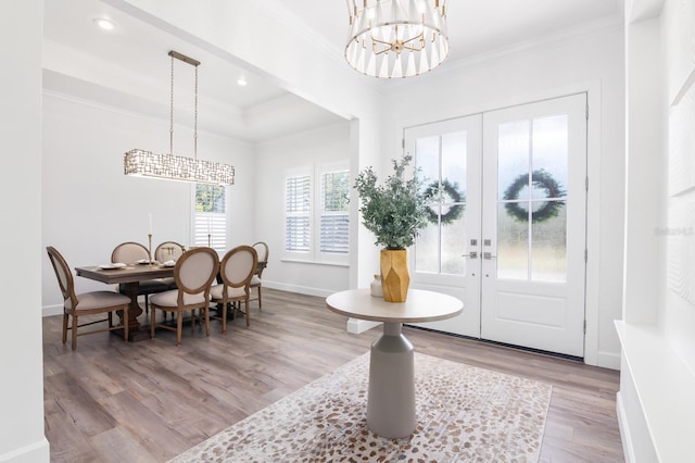 entryway with french doors, light wood-type flooring, a tray ceiling, crown molding, and a chandelier