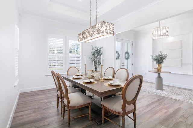 dining room featuring french doors, crown molding, hardwood / wood-style floors, a chandelier, and a tray ceiling