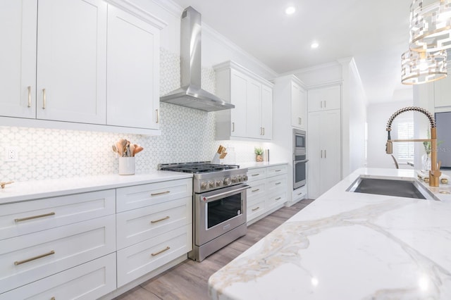 kitchen featuring backsplash, white cabinets, wall chimney range hood, sink, and stainless steel appliances