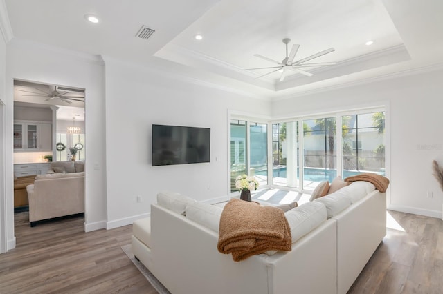 living room featuring a tray ceiling, hardwood / wood-style floors, and ornamental molding