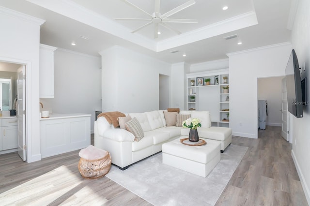 living room featuring light hardwood / wood-style floors, a raised ceiling, ceiling fan, and crown molding