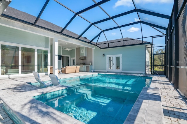 view of pool featuring glass enclosure, french doors, pool water feature, ceiling fan, and a patio area