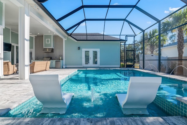 view of swimming pool featuring french doors, an outdoor kitchen, pool water feature, glass enclosure, and a patio area