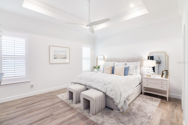 bedroom featuring a tray ceiling, light hardwood / wood-style flooring, ceiling fan, and crown molding