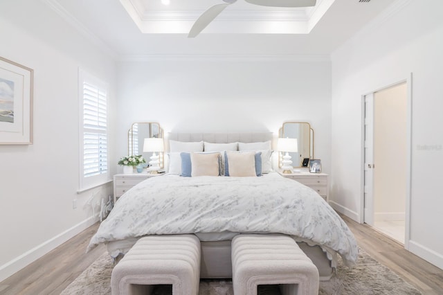 bedroom featuring a raised ceiling, light hardwood / wood-style flooring, ceiling fan, and ornamental molding