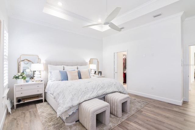 bedroom featuring ceiling fan, hardwood / wood-style floors, a walk in closet, a closet, and ornamental molding