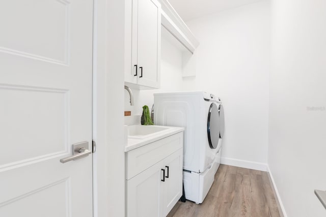 clothes washing area featuring cabinets, separate washer and dryer, light hardwood / wood-style floors, and sink