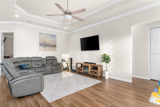 living room featuring a raised ceiling, ceiling fan, and ornamental molding