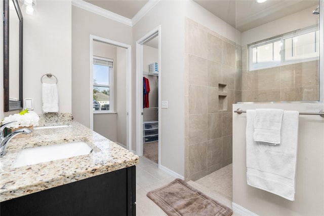 bathroom with crown molding, tile patterned flooring, vanity, and tiled shower