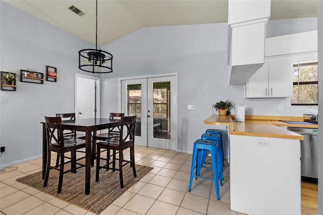 tiled dining space with french doors, vaulted ceiling, and a notable chandelier