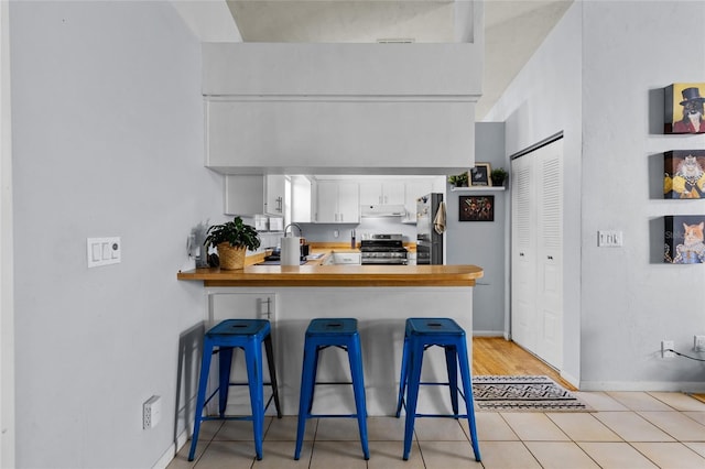 kitchen with white cabinets, a breakfast bar, kitchen peninsula, and stainless steel appliances