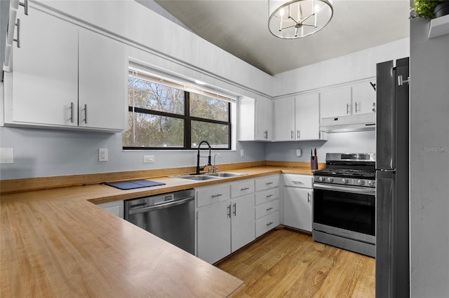 kitchen featuring sink, stainless steel appliances, an inviting chandelier, pendant lighting, and white cabinets