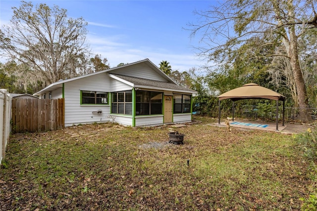 rear view of house featuring a gazebo, a sunroom, and a yard