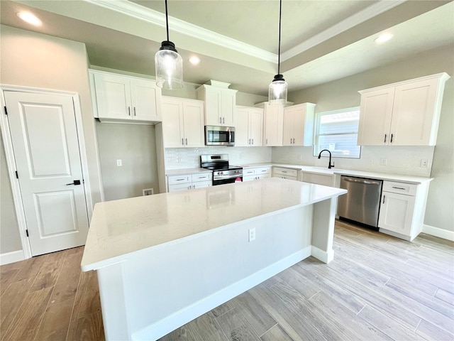 kitchen with decorative light fixtures, white cabinets, appliances with stainless steel finishes, and a kitchen island