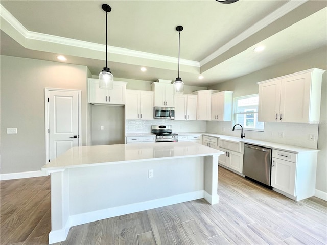 kitchen with stainless steel appliances, white cabinetry, and a center island