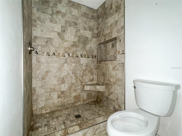 bathroom featuring a tile shower and toilet