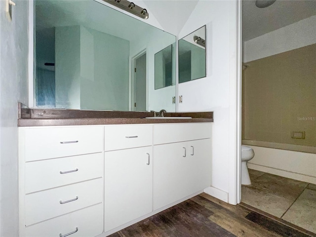 full bathroom featuring hardwood / wood-style flooring, shower / bath combination, vanity, vaulted ceiling, and toilet