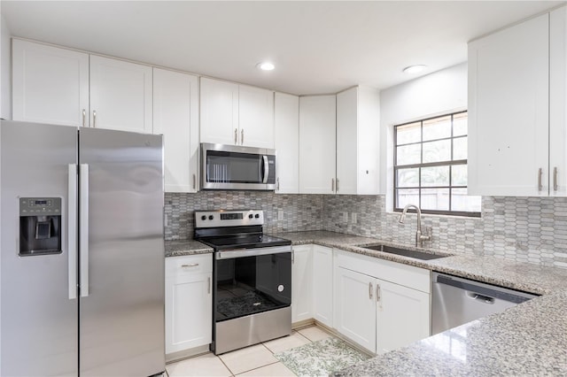 kitchen with white cabinetry, sink, light stone counters, and stainless steel appliances