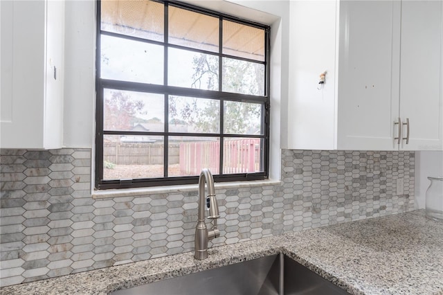 room details with white cabinetry, light stone countertops, sink, and decorative backsplash