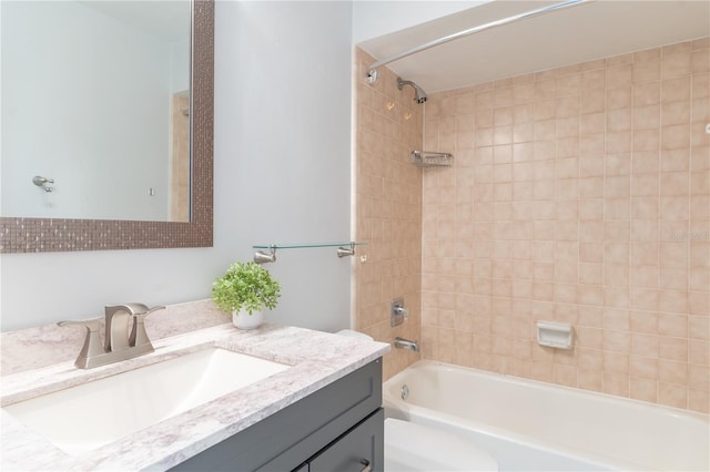 full bathroom featuring tiled shower / bath combo, vanity, and toilet