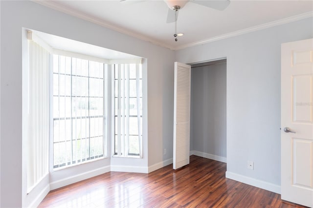 unfurnished bedroom featuring ornamental molding, dark wood-type flooring, ceiling fan, and a closet