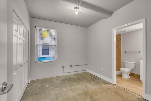 interior space featuring ensuite bathroom, a closet, and beamed ceiling