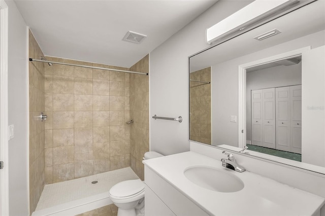 bathroom with tiled shower, tile patterned flooring, vanity, and toilet