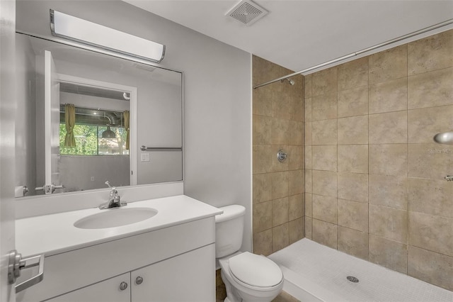 bathroom with tiled shower, vanity, and toilet