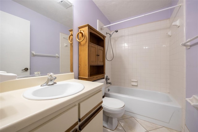 full bathroom with a textured ceiling, tiled shower / bath, toilet, tile patterned floors, and vanity