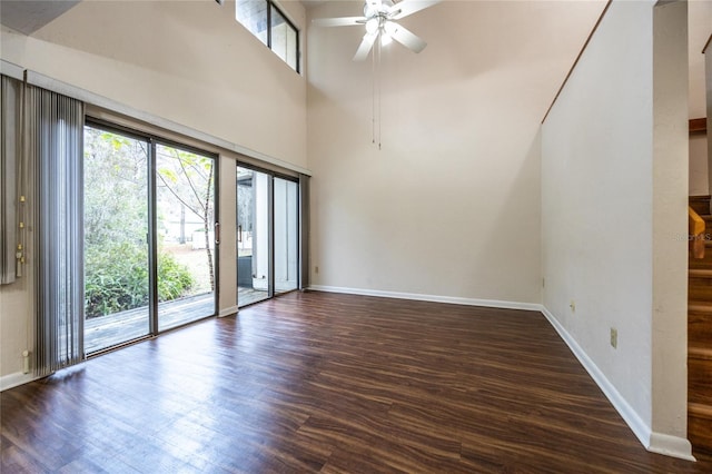 spare room with a towering ceiling, dark wood-type flooring, and ceiling fan