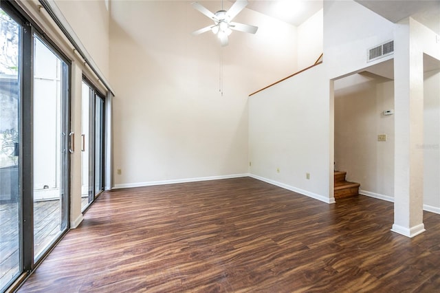 unfurnished room with a towering ceiling, dark hardwood / wood-style flooring, and ceiling fan