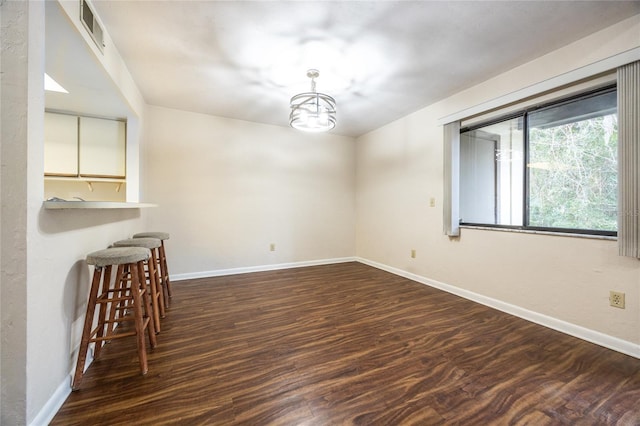 unfurnished dining area featuring an inviting chandelier and dark wood-type flooring