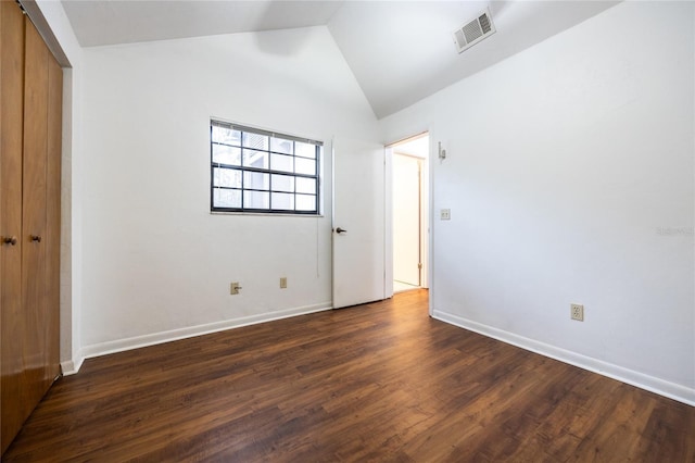 unfurnished bedroom featuring lofted ceiling, dark wood-type flooring, and a closet