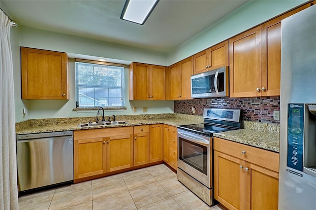 kitchen with light stone countertops, decorative backsplash, stainless steel appliances, sink, and light tile patterned floors