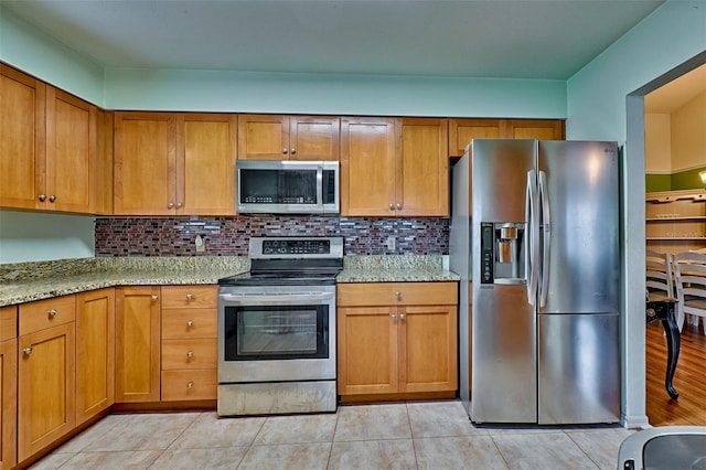 kitchen with tasteful backsplash, light stone counters, light tile patterned floors, and stainless steel appliances