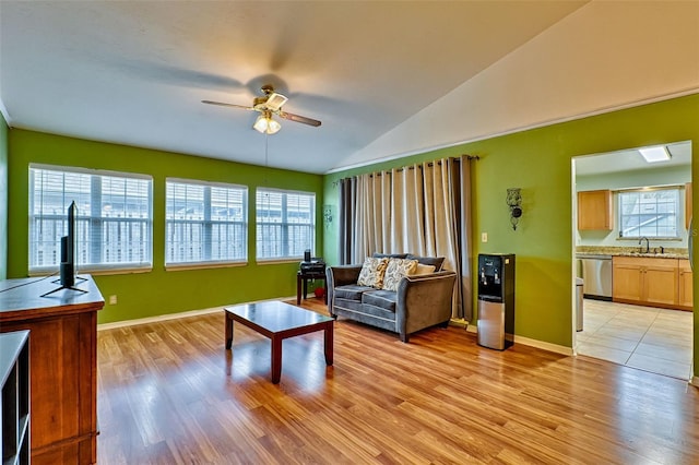 living room with plenty of natural light, ceiling fan, light wood-type flooring, and vaulted ceiling