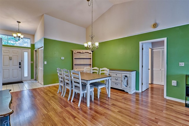 dining space with a chandelier, high vaulted ceiling, and light hardwood / wood-style flooring