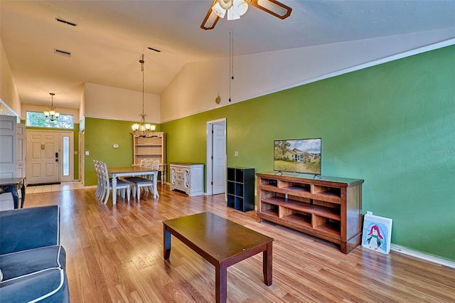 living room with light hardwood / wood-style flooring, high vaulted ceiling, and ceiling fan with notable chandelier