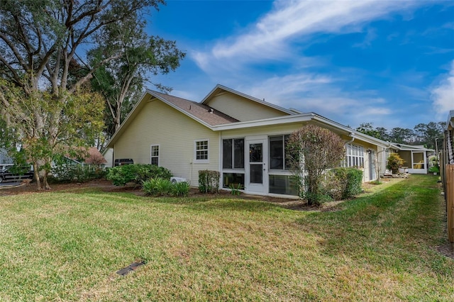 back of property with a yard and a sunroom