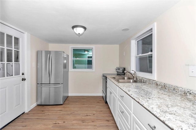 kitchen featuring sink, light wood-type flooring, appliances with stainless steel finishes, light stone counters, and white cabinetry