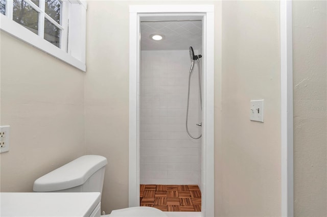 bathroom with vanity, toilet, and tiled shower