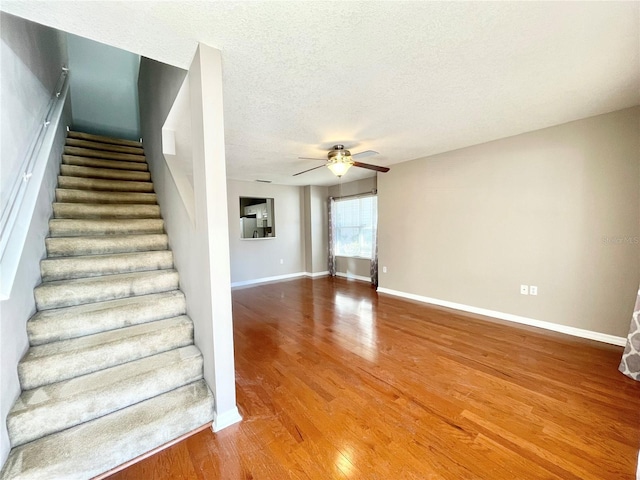 stairway featuring ceiling fan, hardwood / wood-style floors, and a textured ceiling