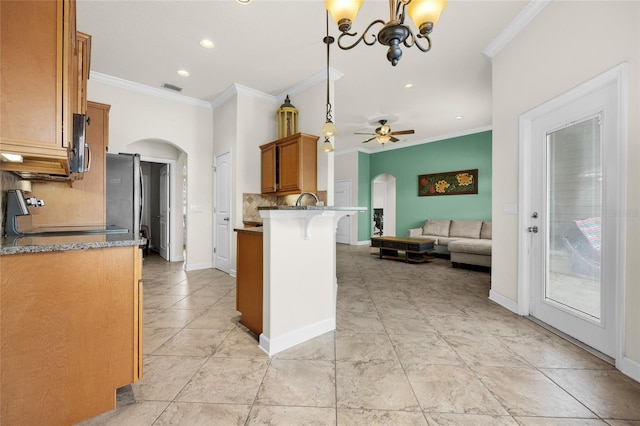 kitchen featuring a breakfast bar area, stainless steel appliances, hanging light fixtures, crown molding, and ceiling fan with notable chandelier