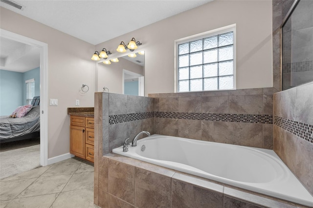 bathroom with tile patterned floors, a relaxing tiled tub, and vanity