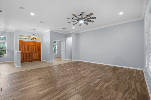 unfurnished living room with ceiling fan with notable chandelier and ornamental molding